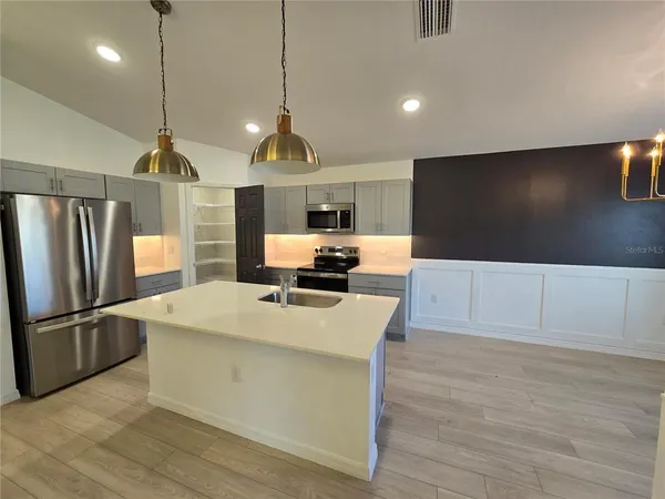 a large kitchen with kitchen island a counter space a sink appliances and cabinets