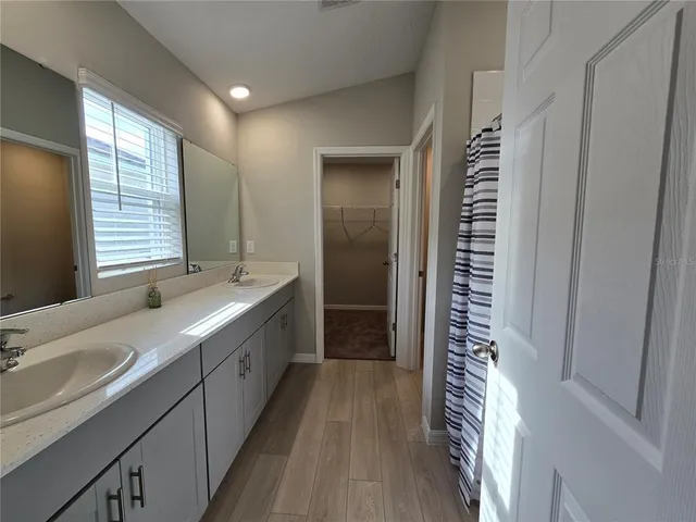 a bathroom with a double vanity sink a large mirror and a bathtub