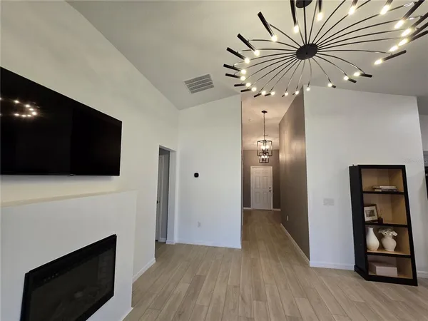 a view of an empty room with wooden floor and a fireplace