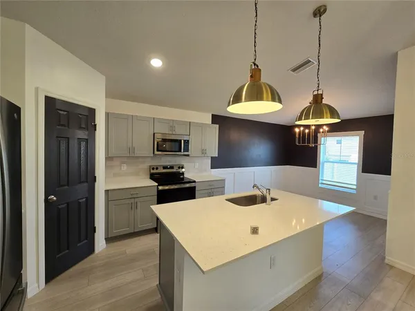 a kitchen with stainless steel appliances a stove a refrigerator a sink a center island and wooden floor