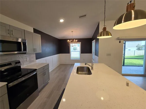 a kitchen with stainless steel appliances a stove a sink a microwave a refrigerator and cabinets