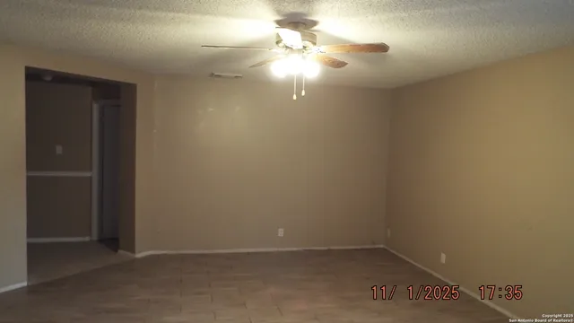 an empty room with a fan & a window