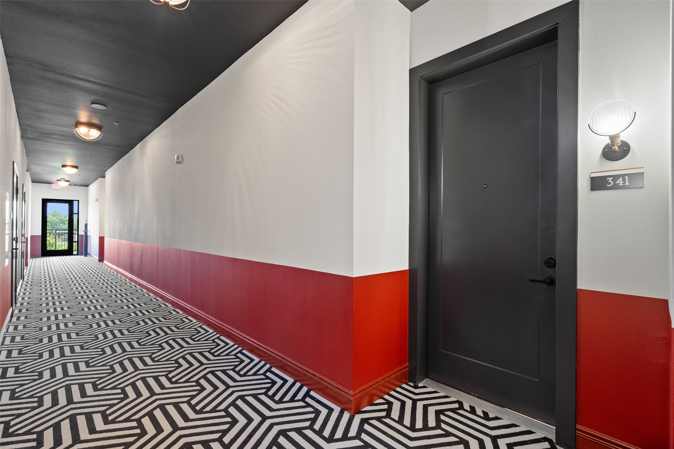 4510 Terry-O Lane, Unit 341 Austin, TX 78745 - Photo 3 of 40 Inviting common area hallway with a bold geometric pattern floor, contrasting red and white walls, and contemporary overhead lighting
