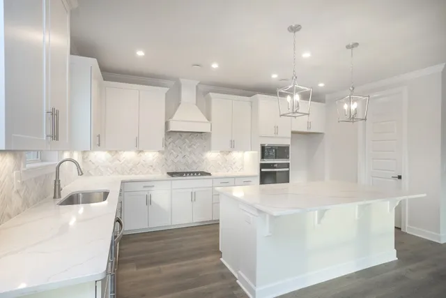 a large white kitchen with kitchen island a sink a stove and a refrigerator
