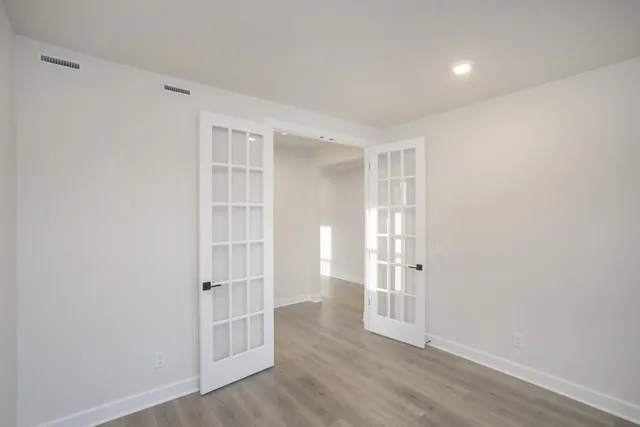 an empty room with wooden floor and windows