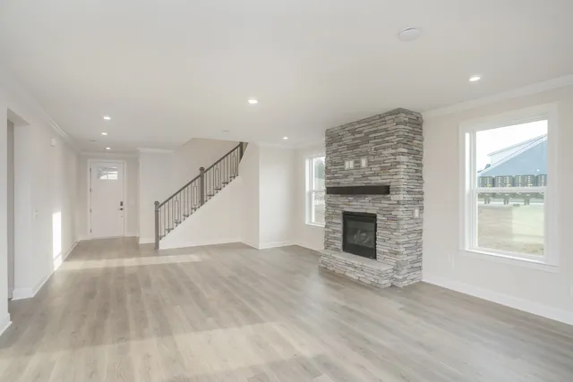an empty room with wooden floor fireplace and windows