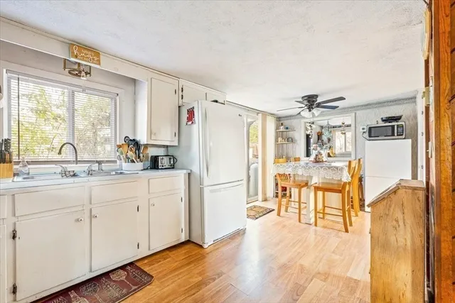 a kitchen with granite countertop a refrigerator a sink a dining table and chairs