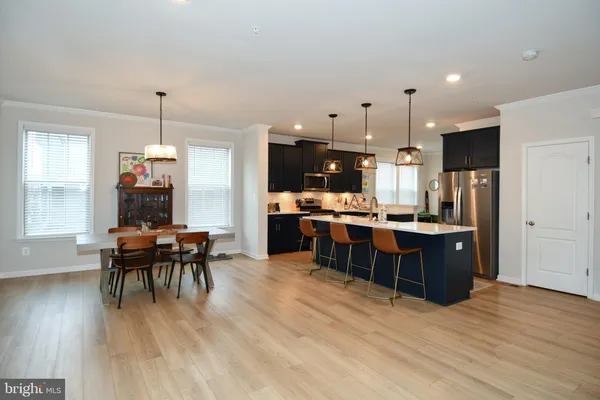 a kitchen with stainless steel appliances kitchen island granite countertop a table chairs and a refrigerator