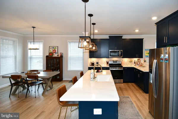 a kitchen with stainless steel appliances kitchen island granite countertop a refrigerator a stove a sink dishwasher with a dining table and chairs with wooden floor