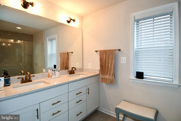 a bathroom with a double vanity sink a mirror and a bathtub