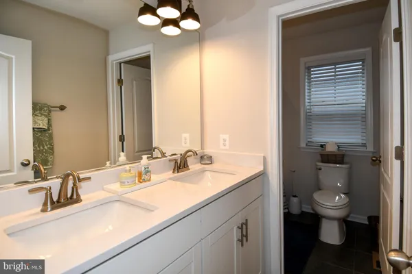 a bathroom with a granite countertop sink a toilet and a mirror