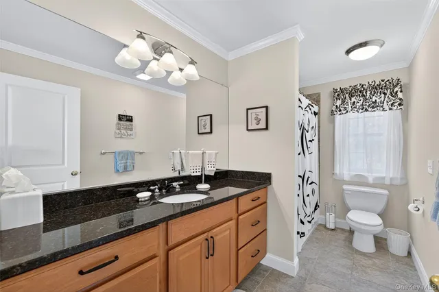 a spacious bathroom with a granite countertop sink a toilet and a mirror