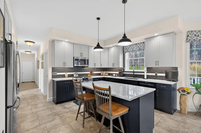a kitchen with stainless steel appliances granite countertop a sink a stove a refrigerator and chairs