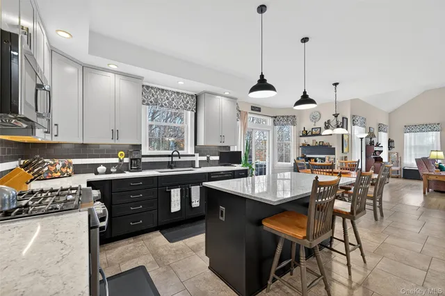 a kitchen with stainless steel appliances granite countertop sink stove and white cabinets with wooden floor