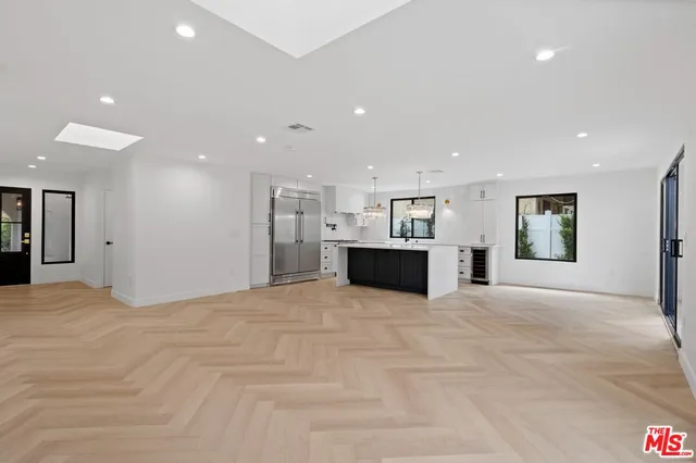 a view of an empty room with kitchen and a sink