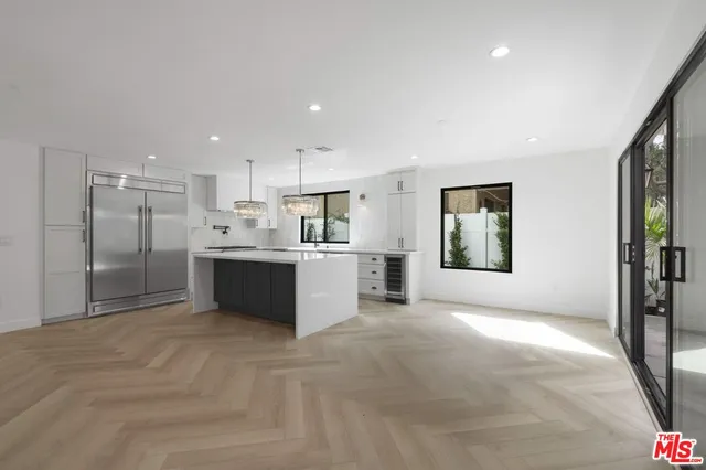 a large white kitchen with a refrigerator a counter top space and a sink