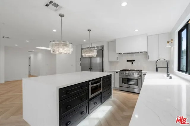 a large kitchen with kitchen island a stove a sink a center island and stainless steel appliances