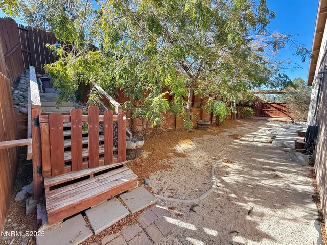 a view of a backyard with wooden fence and trees
