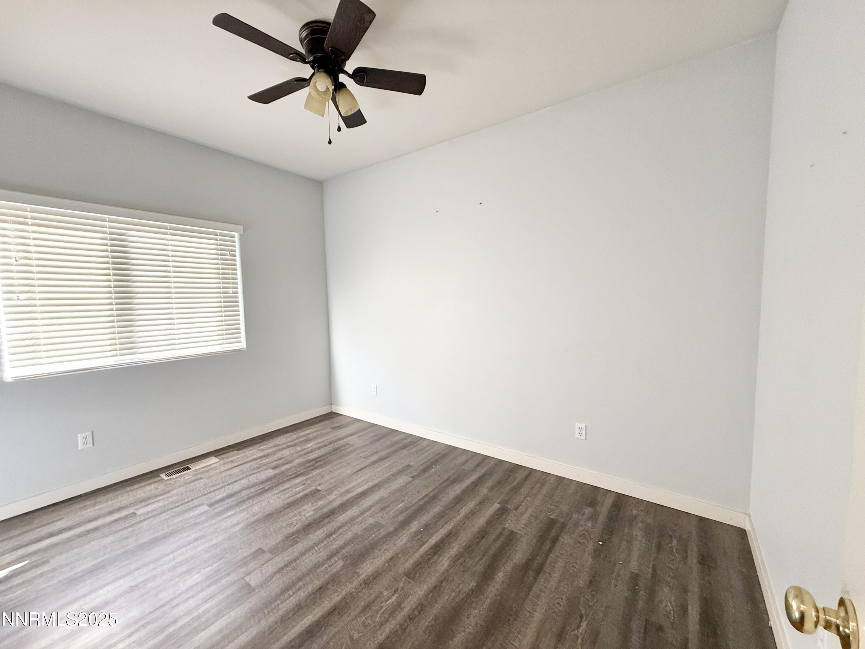 955 Aster Lane Fernley, NV 89408 - Photo 7 of 14 an empty room with wooden floor chandelier fan and windows
