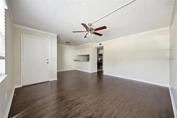 an empty room with wooden floor and ceiling fan