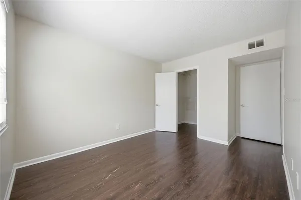 a view of an empty room with wooden floor and closet