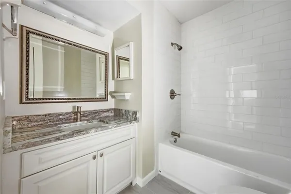 a bathroom with a granite countertop sink mirror toilet and bathtub