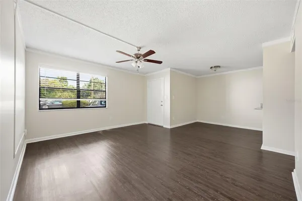 an empty room with wooden floor chandelier and windows
