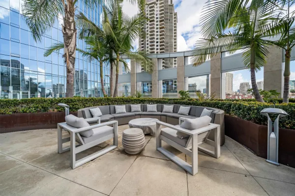 a group of couches sitting in a patio with a barbeque grill and palm trees