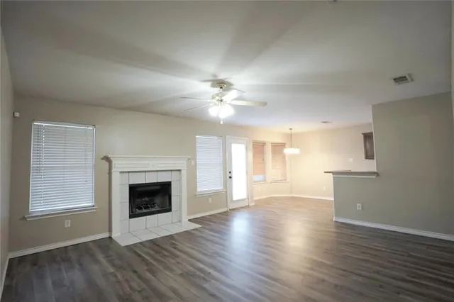 a view of a livingroom with a fireplace a ceiling fan and wooden floor