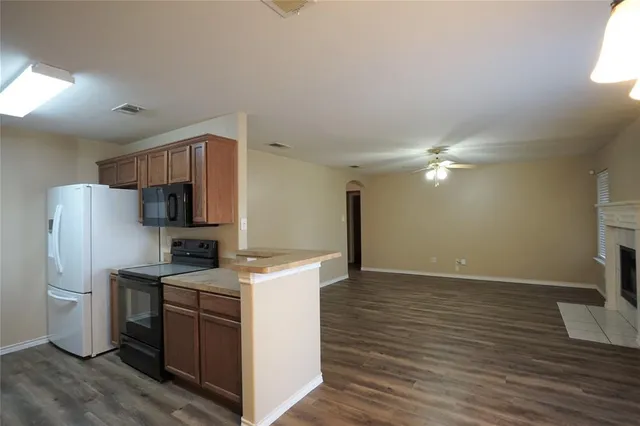 a view of a kitchen with a sink and dishwasher a refrigerator with wooden floor