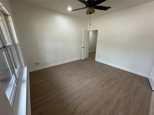 an empty room with wooden floor fan and window