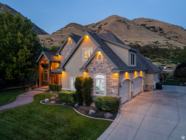 687 South 2080th Street East Springville, UT 84663 - Photo 89 of 149 Stone and stucco exterior featuring a multi-car garage, a covered entry with exposed timber accents, and a winding concrete driveway