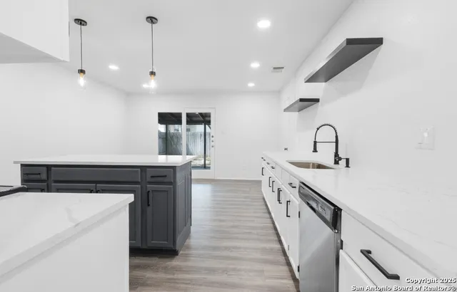a kitchen with kitchen island a sink and a stove with wooden floors