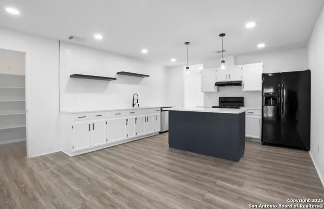 a large kitchen with stainless steel appliances kitchen island granite countertop a stove a refrigerator a sink and a oven