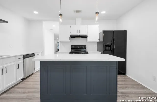 a kitchen with granite countertop a refrigerator a oven a stove and a wooden floors