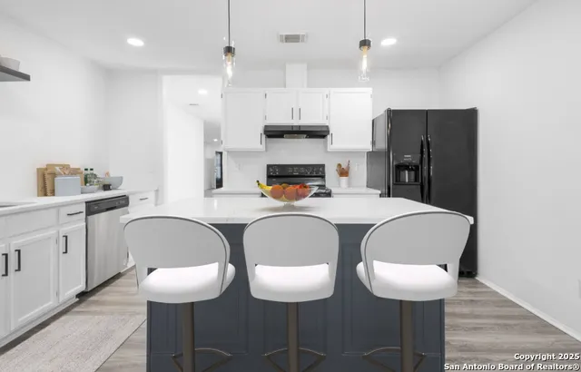 a kitchen with stainless steel appliances granite countertop a table chairs and a refrigerator