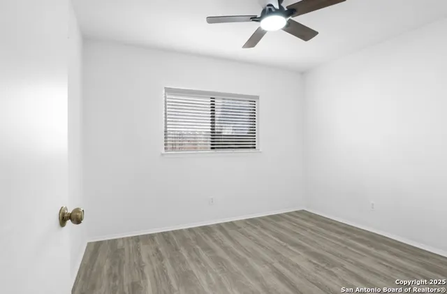 an empty room with a window and a ceiling fan