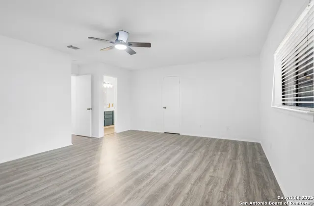 an empty room with wooden floor and windows