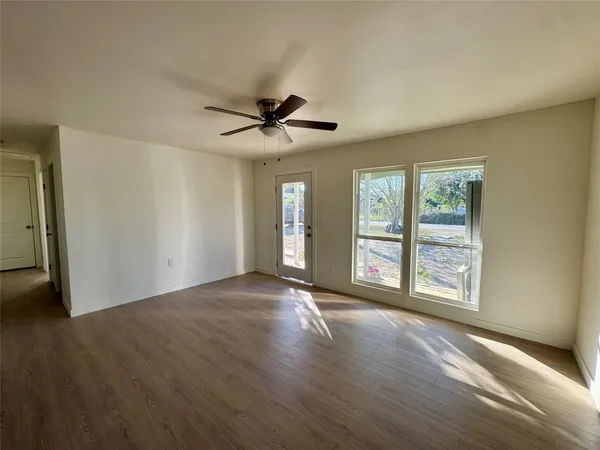 a view of an empty room with a window and wooden floor