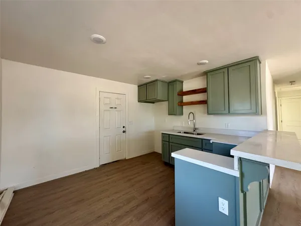 a view of a kitchen with a stove wooden floor and cabinets