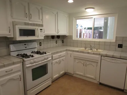 a kitchen with white cabinets and white appliances