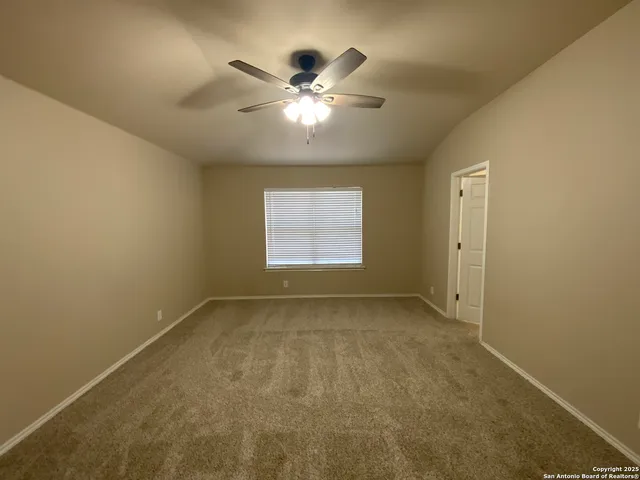 an empty room with chandelier fan and windows