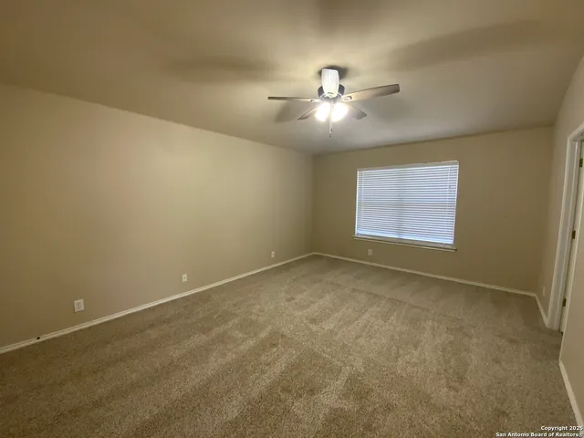 an empty room with a window and ceiling fan
