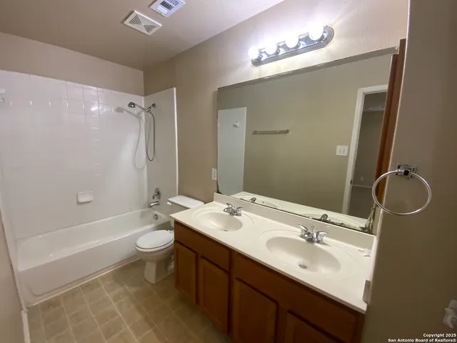 a bathroom with a double vanity sink toilet mirror and bathtub