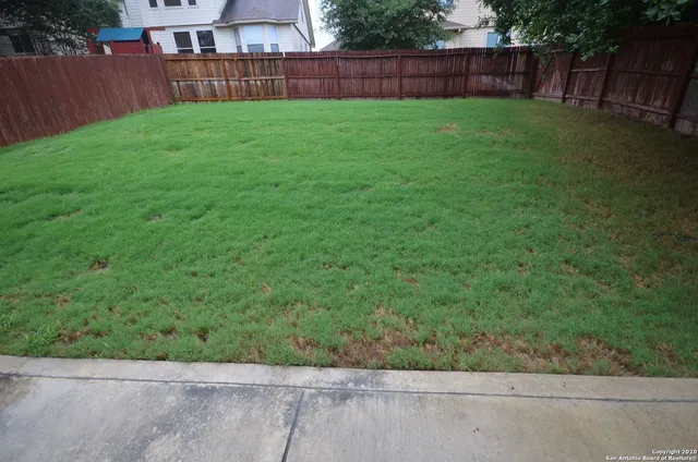 a view of a yard with wooden fence