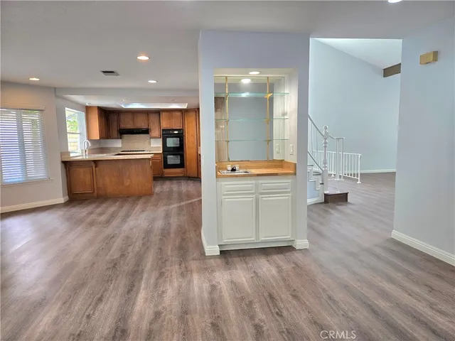 a room with stainless steel appliances kitchen island wooden floors and view living room