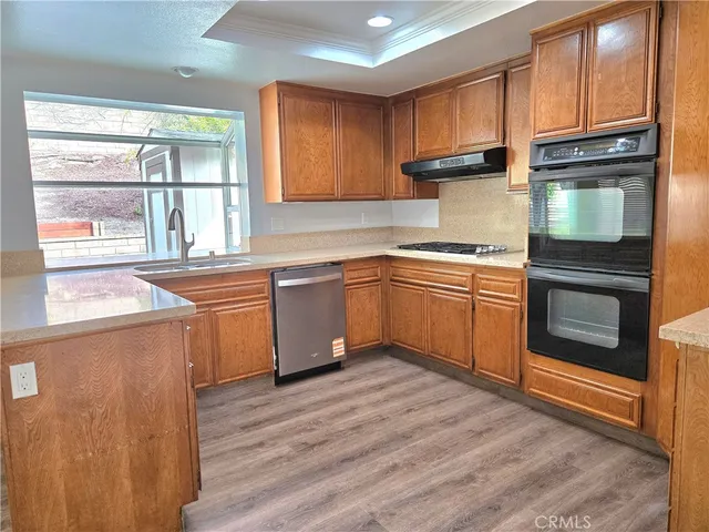 a kitchen with stainless steel appliances granite countertop wooden cabinets a sink and dishwasher with wooden floor