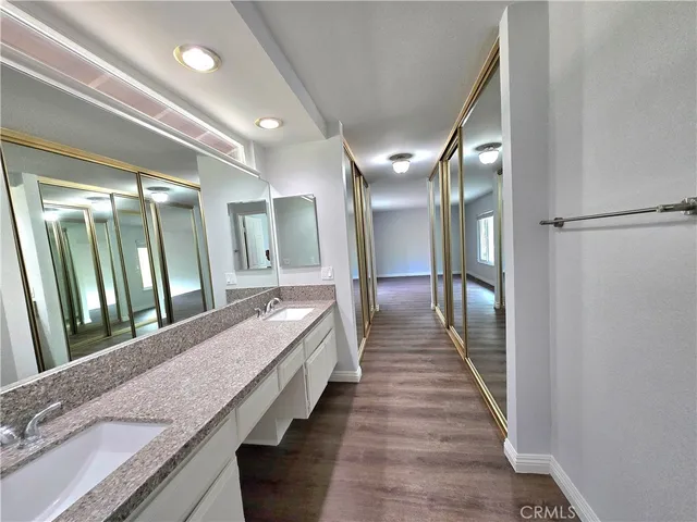 a bathroom with a granite countertop double vanity and a large mirror