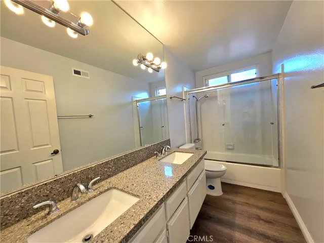 a bathroom with a granite countertop double vanity sink and mirror with shower