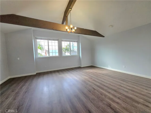 an empty room with wooden floor chandelier and windows